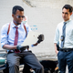 Spiral: From the Book of Saw's Chris Rock examines a piece of paper while sitting on a car, Max Minghella looks on.